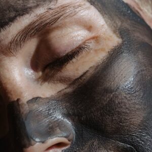 Crop face of relaxing blond lady closing eyes with clay mask on face during beauty procedure